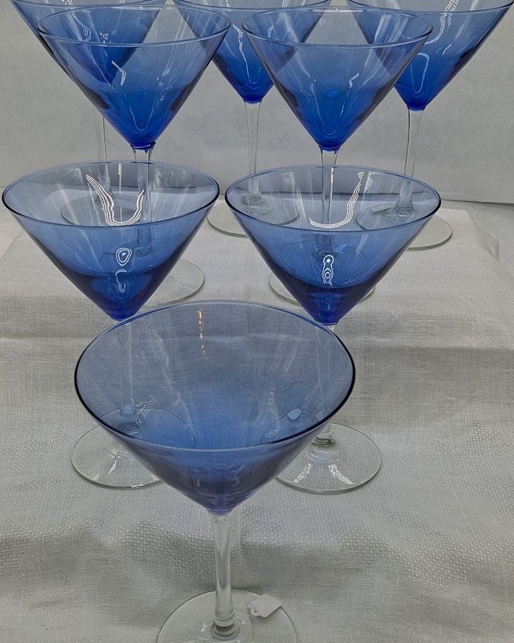 Set of cobalt blue large martini glasses with crystal clear stems arranged in a display