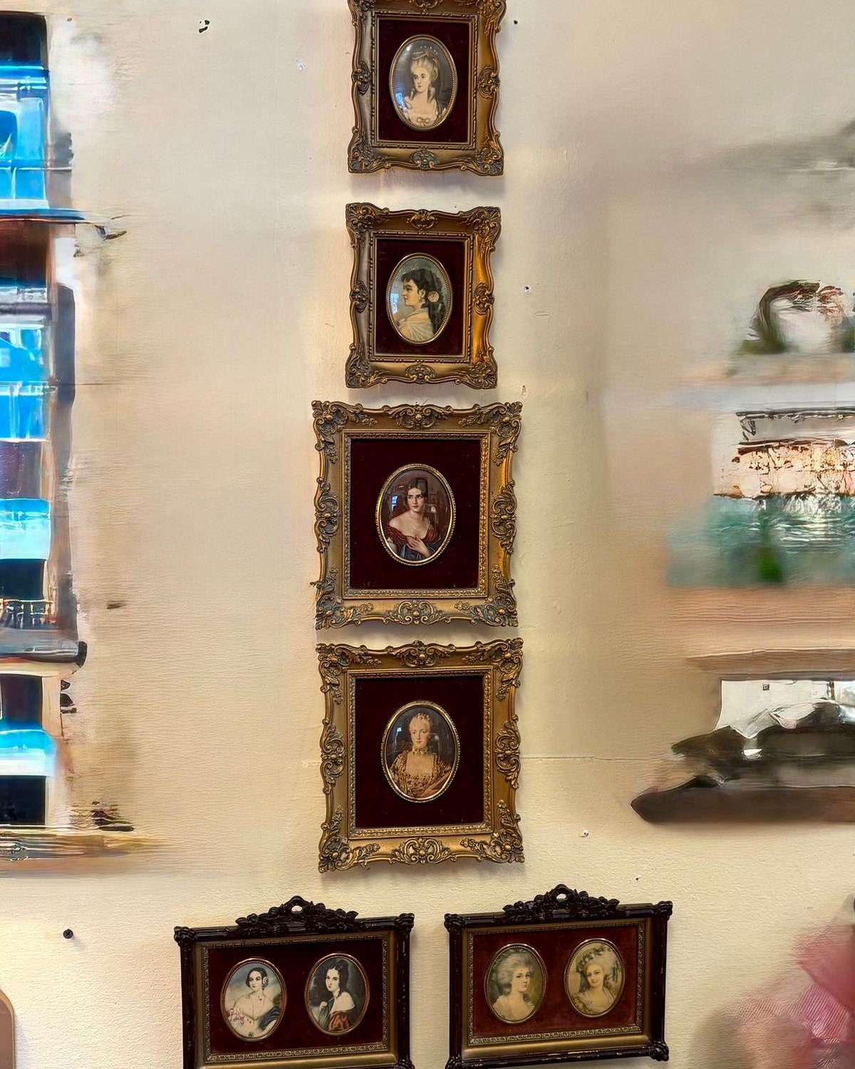 A vertical column of Cameo Creation portraits showing elegant women in ornate gold frames with deep red velvet mats on a shop wall.