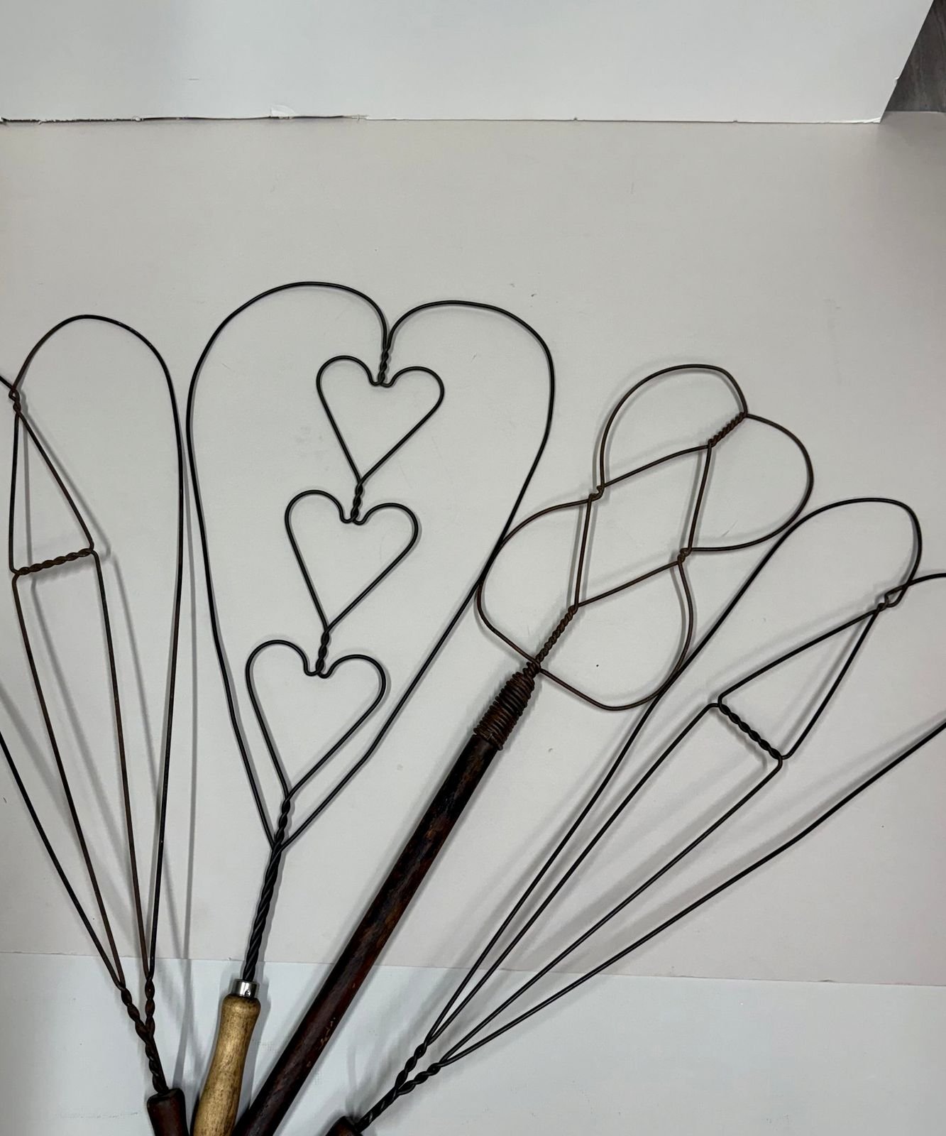 Collection of vintage 1920s wire rug beaters with heart and loop patterns and wooden handles